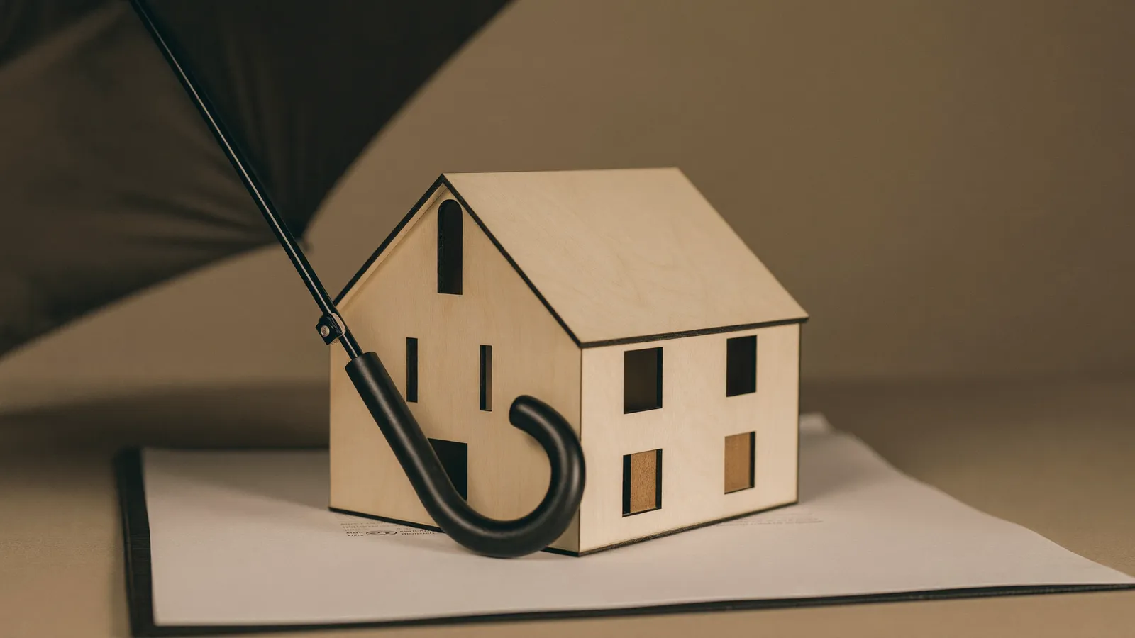 Parapluie au-dessus d'une maquette de maison en bois
