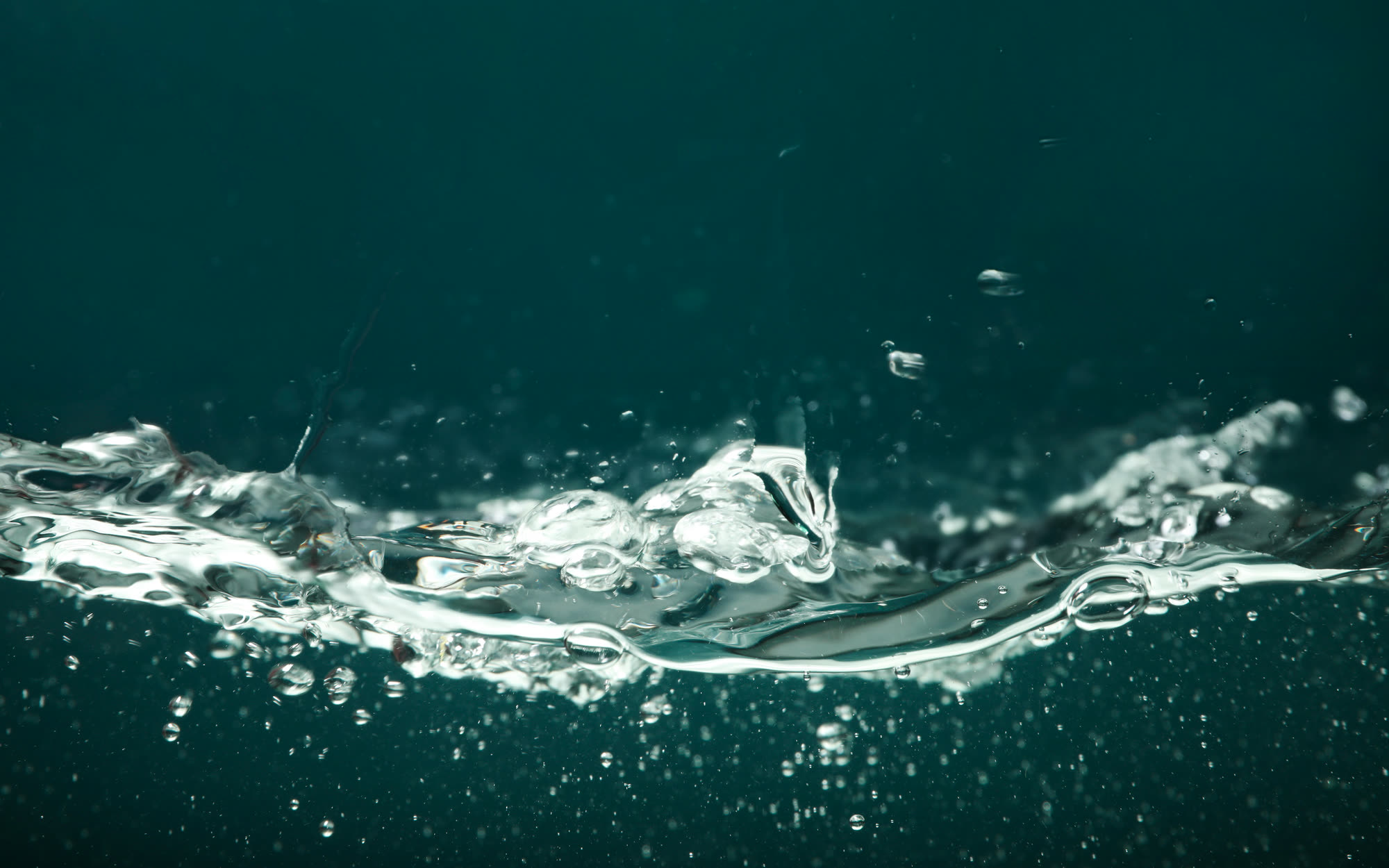Klares, fließendes Wasser vor einem tiefblau-grünen Hintergrund