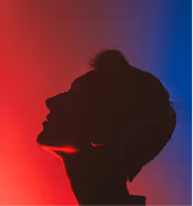 Silhouette of a person's profile against a red and blue gradient background.