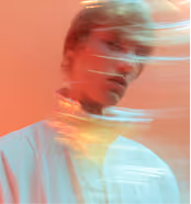 Blurred portrait of a person with motion trails against a warm, reddish background.