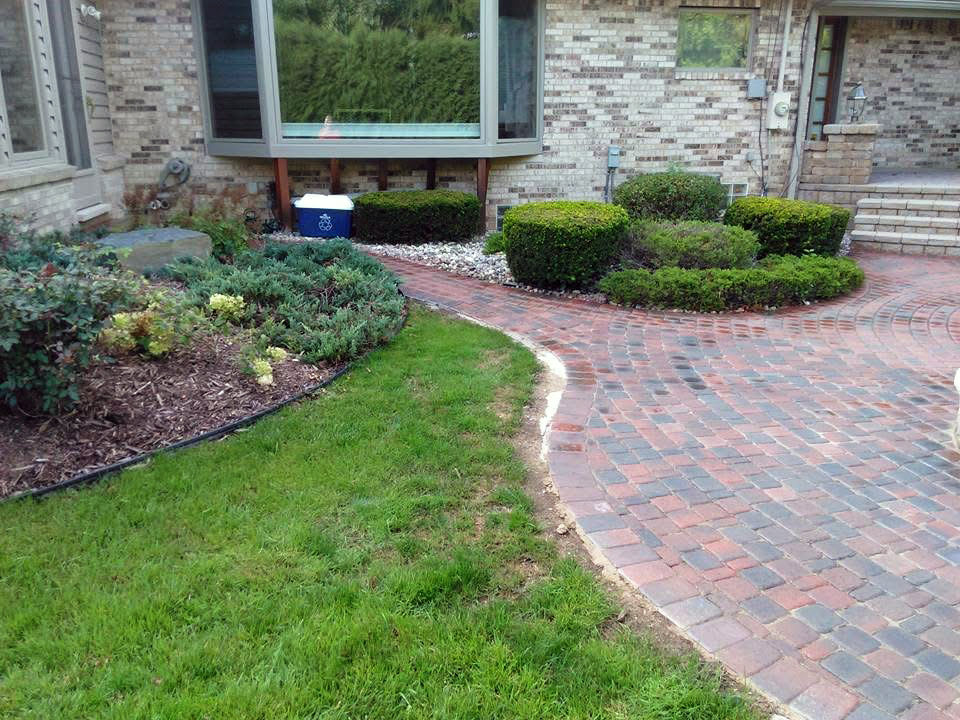 heritage landscape Professional hardscape and landscape integration, showcasing custom brick paving alongside maintained shrubbery and lawn borders.