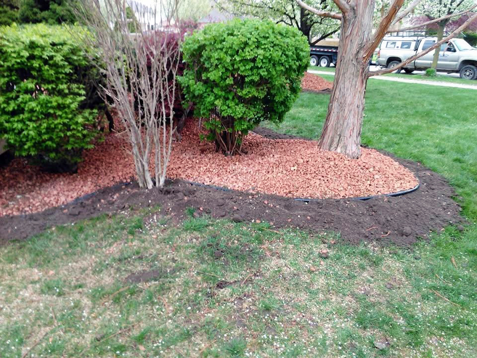 Heritage Landscape Professional landscaping service featuring garden bed edging, red mulch installation, and tree maintenance.