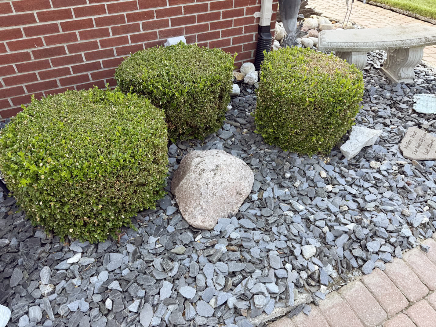 Heritage Landscape Landscaped shrub bed with stone mulch and brick border.