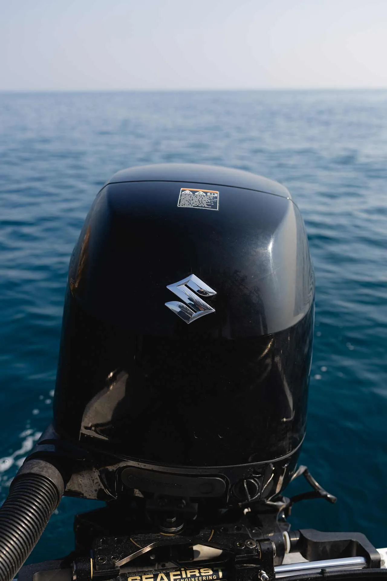 Close-up of a black Suzuki boat motor with the sea in the background.