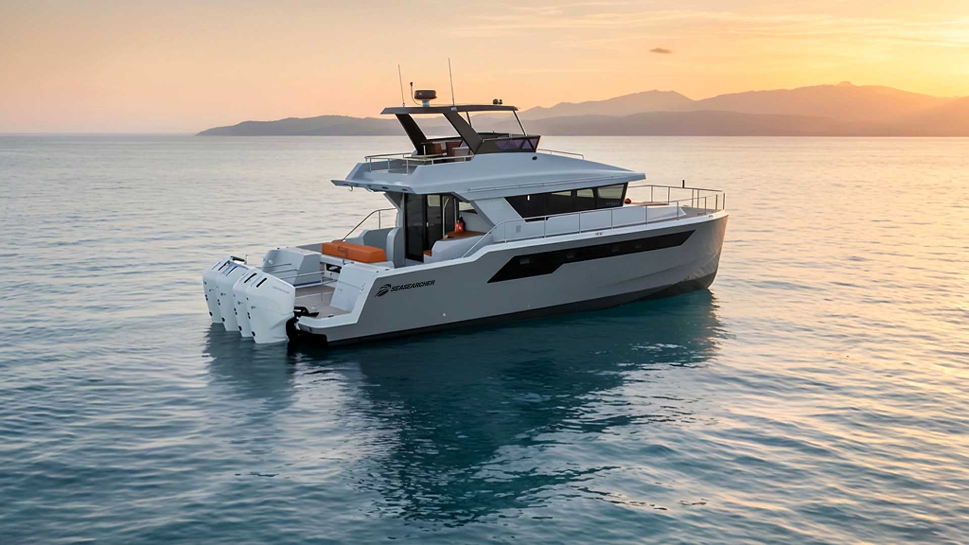 White SeaSearcher motorboat with three outboard engines on calm water at sunset with mountains in the background.