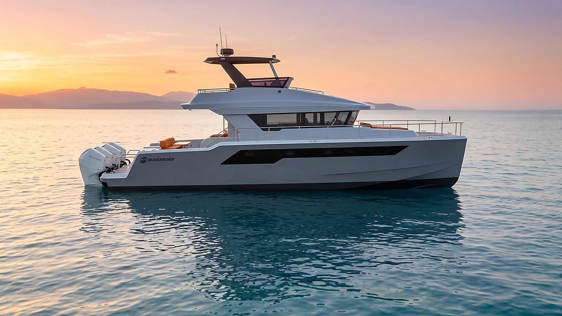 Modern white SeaSearcher motorboat with three outboard engines floating on calm water at sunset.