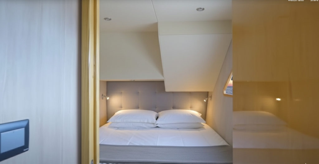 Compact bedroom with a double bed featuring white bedding, two pillows, gray tufted headboard, and reading lights on each side.
