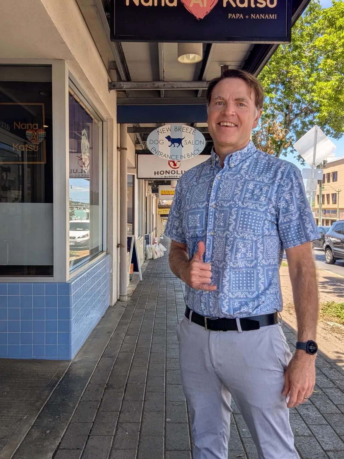 Paul Lovejoy smiling and giving a thumbs-up outside a Honolulu shopfront