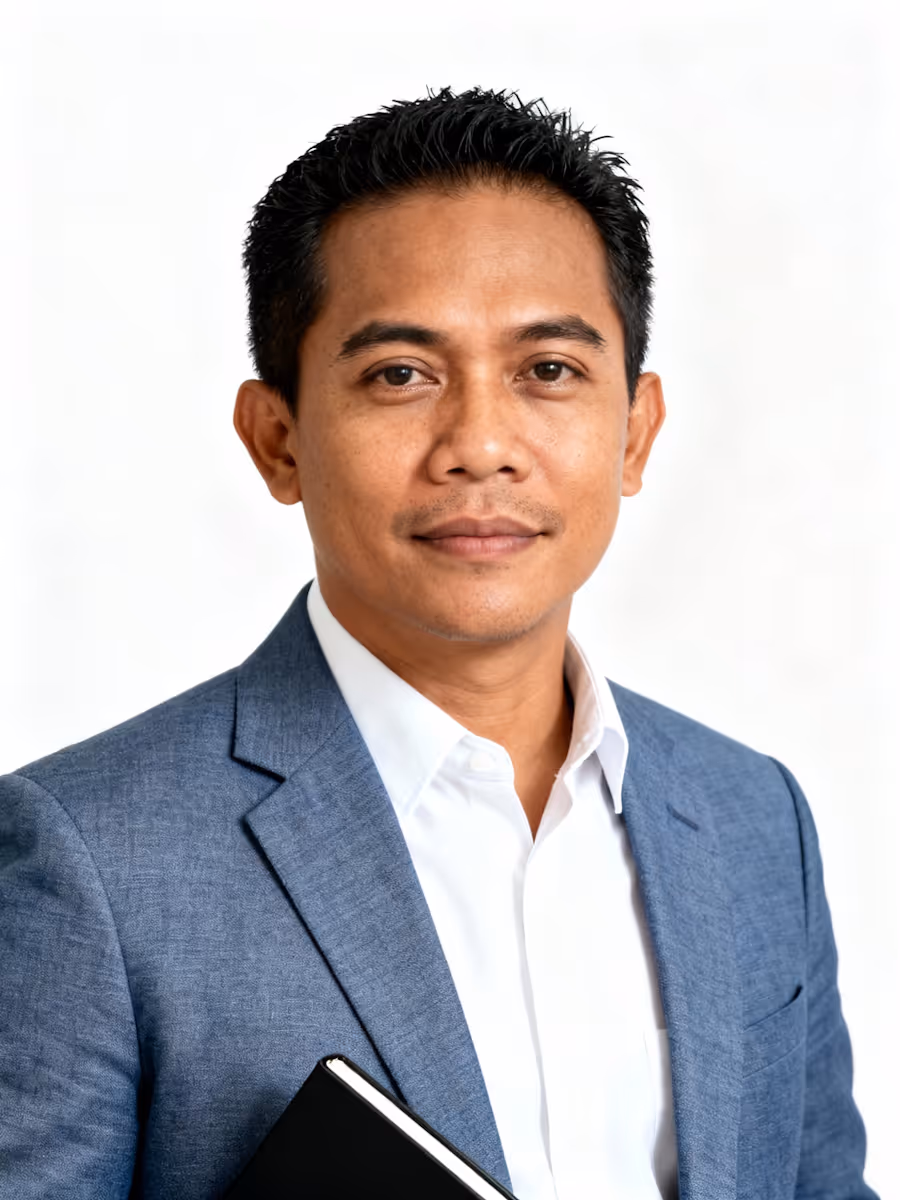 Man in a blue blazer and white shirt holding a black notebook against a white background.