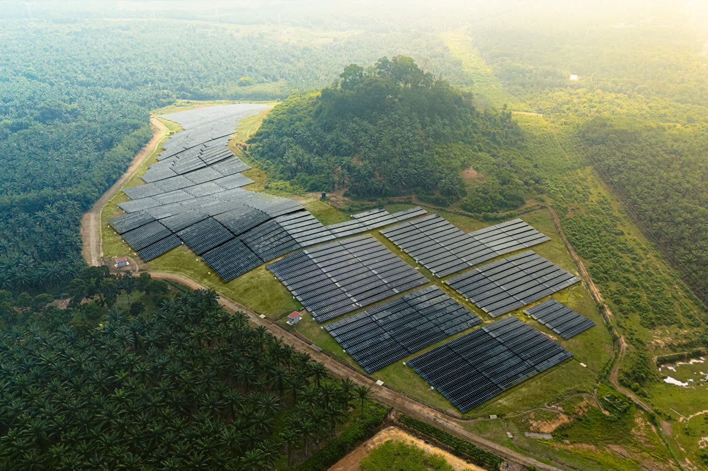 Aerial view of the LSS2 Masjid Tanah solar farm, its panel arrays laid across cleared ground and ringed by palm plantation