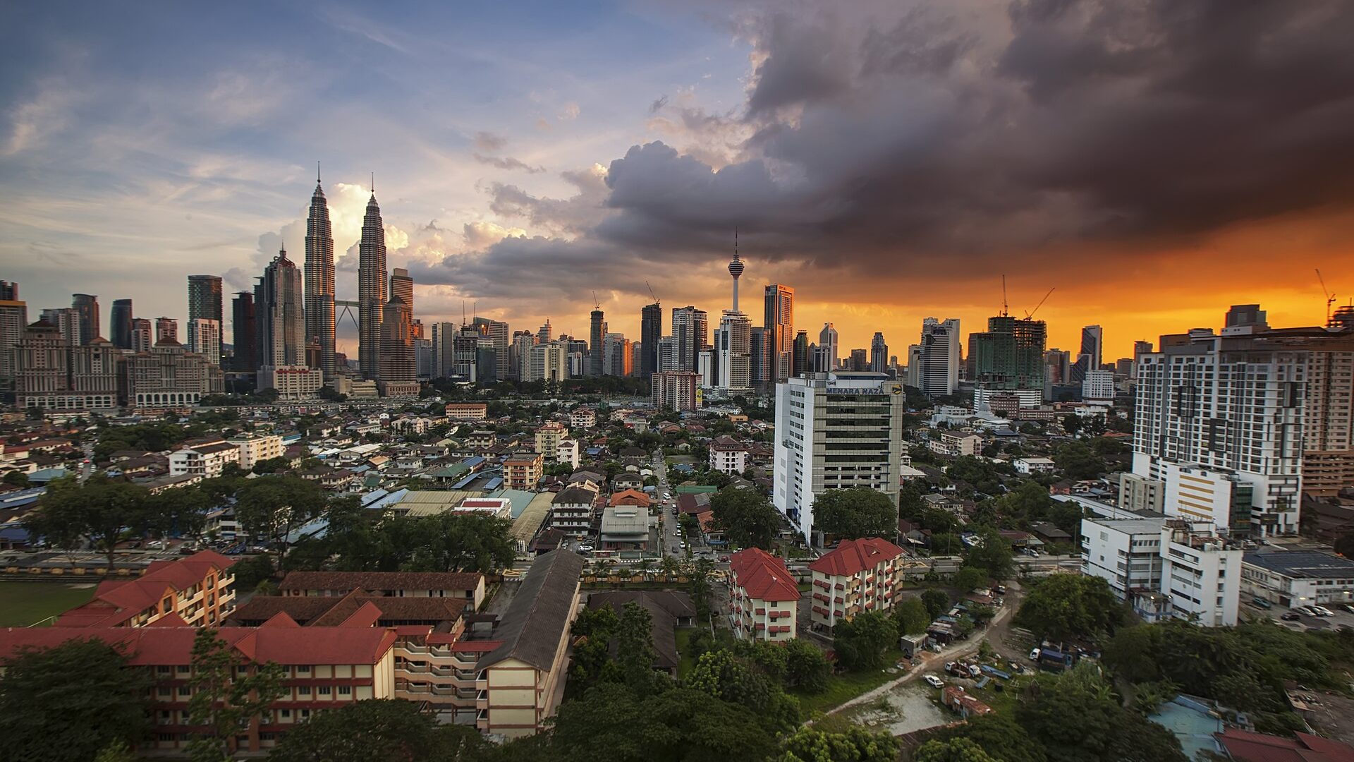 The Kuala Lumpur skyline at dusk, with the city spreading toward the horizon under a clouded sunset
