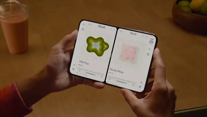 Looping clip of an iPhone Duo held open with two Safari windows side by side in Split View, one showing a store page and the other an article.