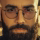 Close-up of a man's face with glasses, a beard, and mustache.