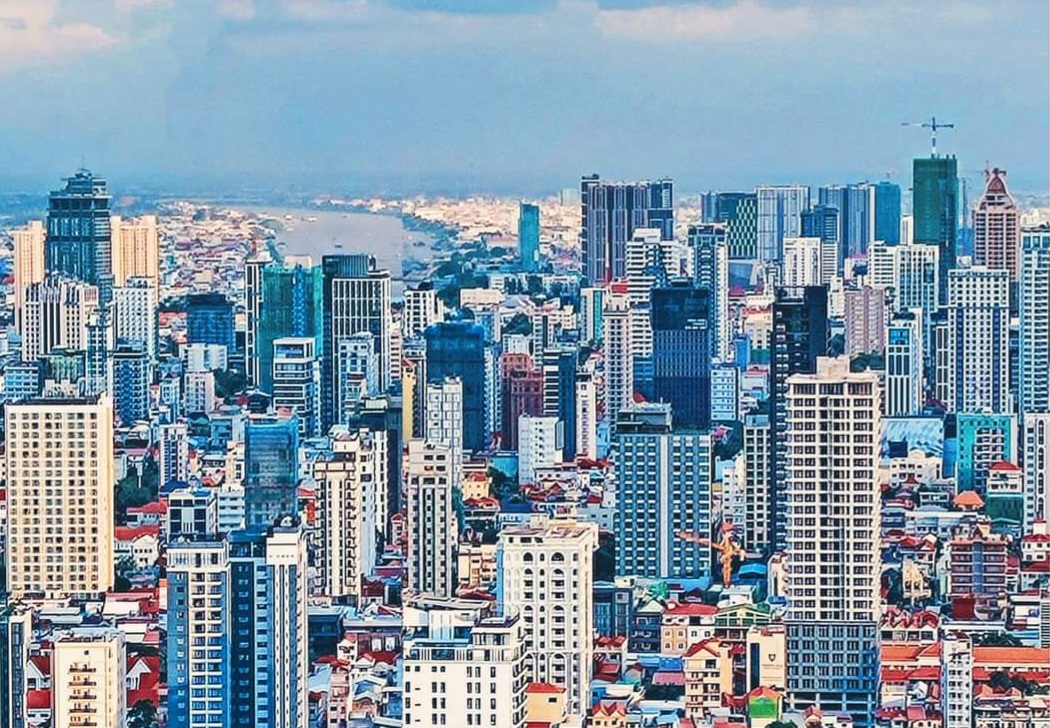Aerial view of the Phnom Penh skyline, high-rise towers packed along the riverfront.