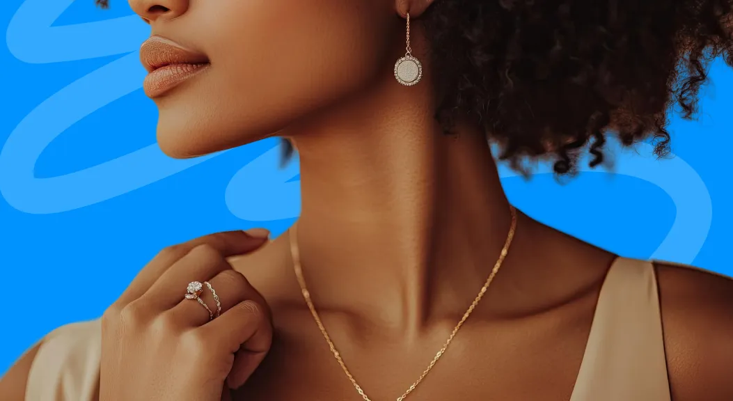 Close-up of a woman wearing a gold necklace, ring and drop earring.
