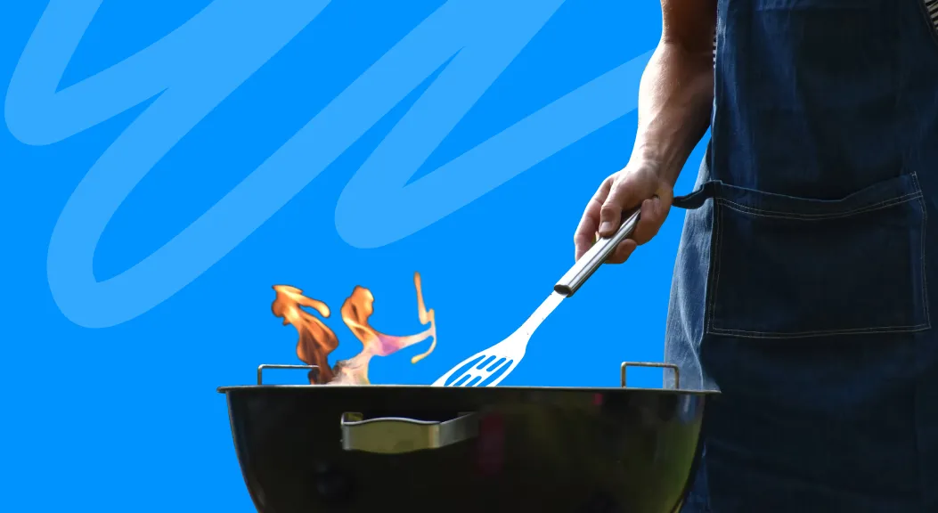 Person in an apron turning food on a kettle barbecue.
