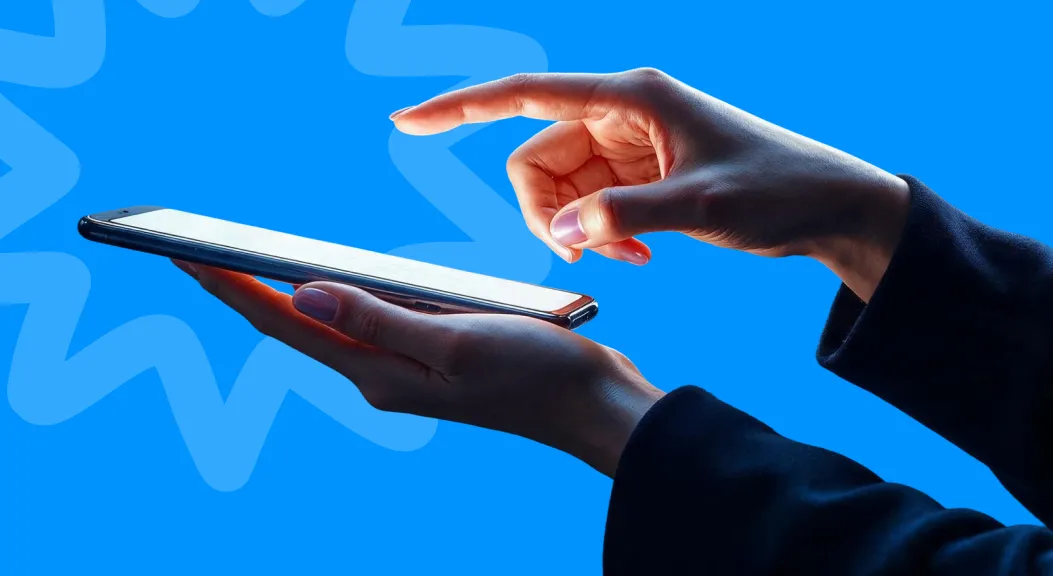 One hand holding a smartphone while another reaches to tap the screen.