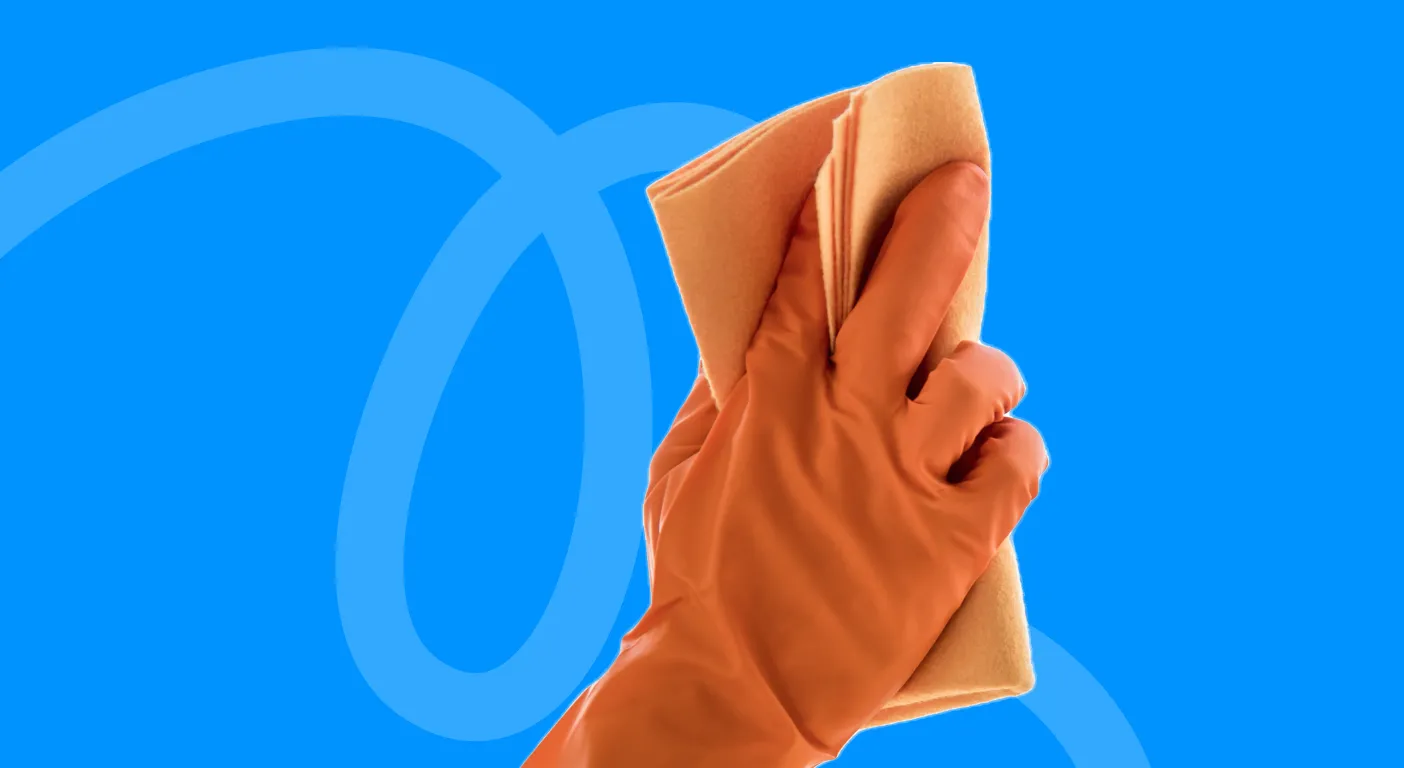 Hand in an orange rubber glove holding a cleaning cloth.