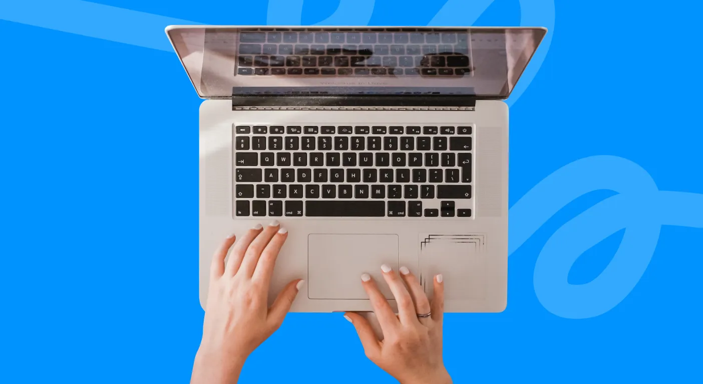 Overhead view of two hands typing on an open laptop.