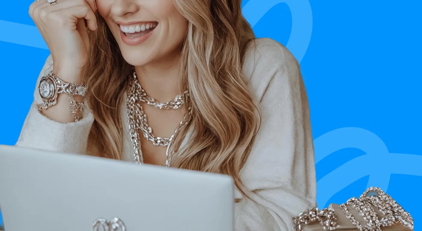 Smiling woman wearing layered silver necklaces and bracelets at a laptop.