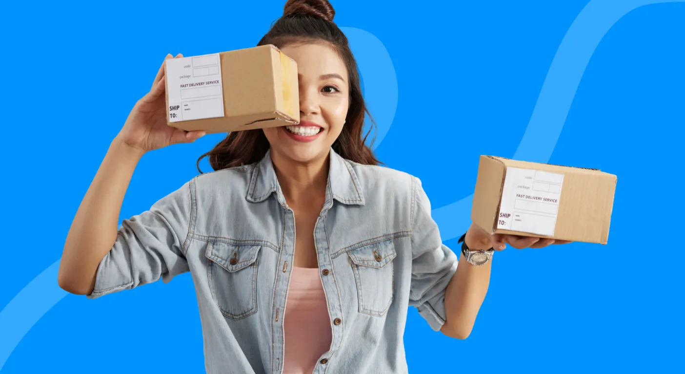 Woman smiling as she holds up two cardboard delivery parcels.