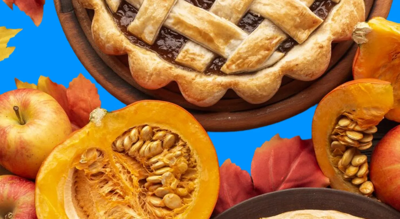 Lattice-topped pie surrounded by apples, squash and autumn leaves.