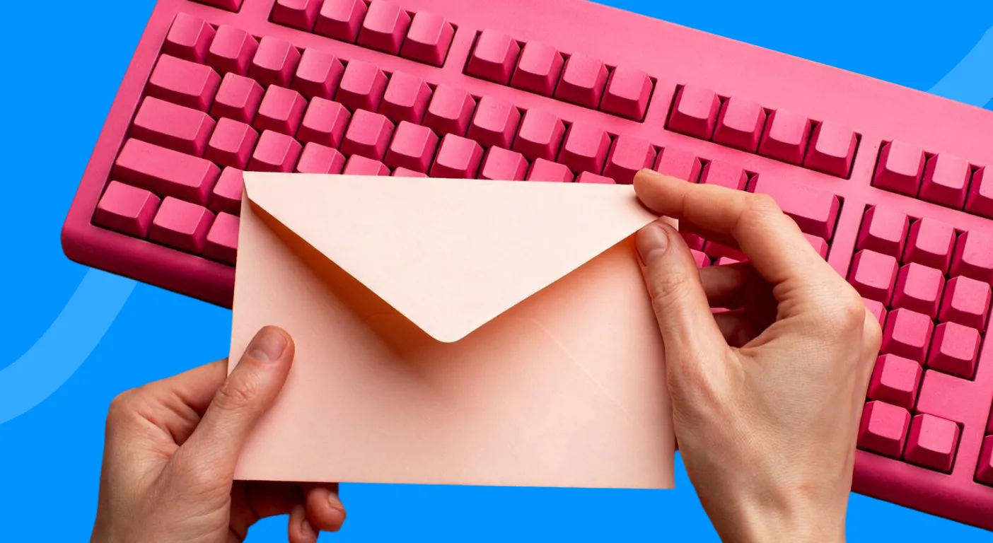 Hands holding a pink envelope in front of a pink keyboard.