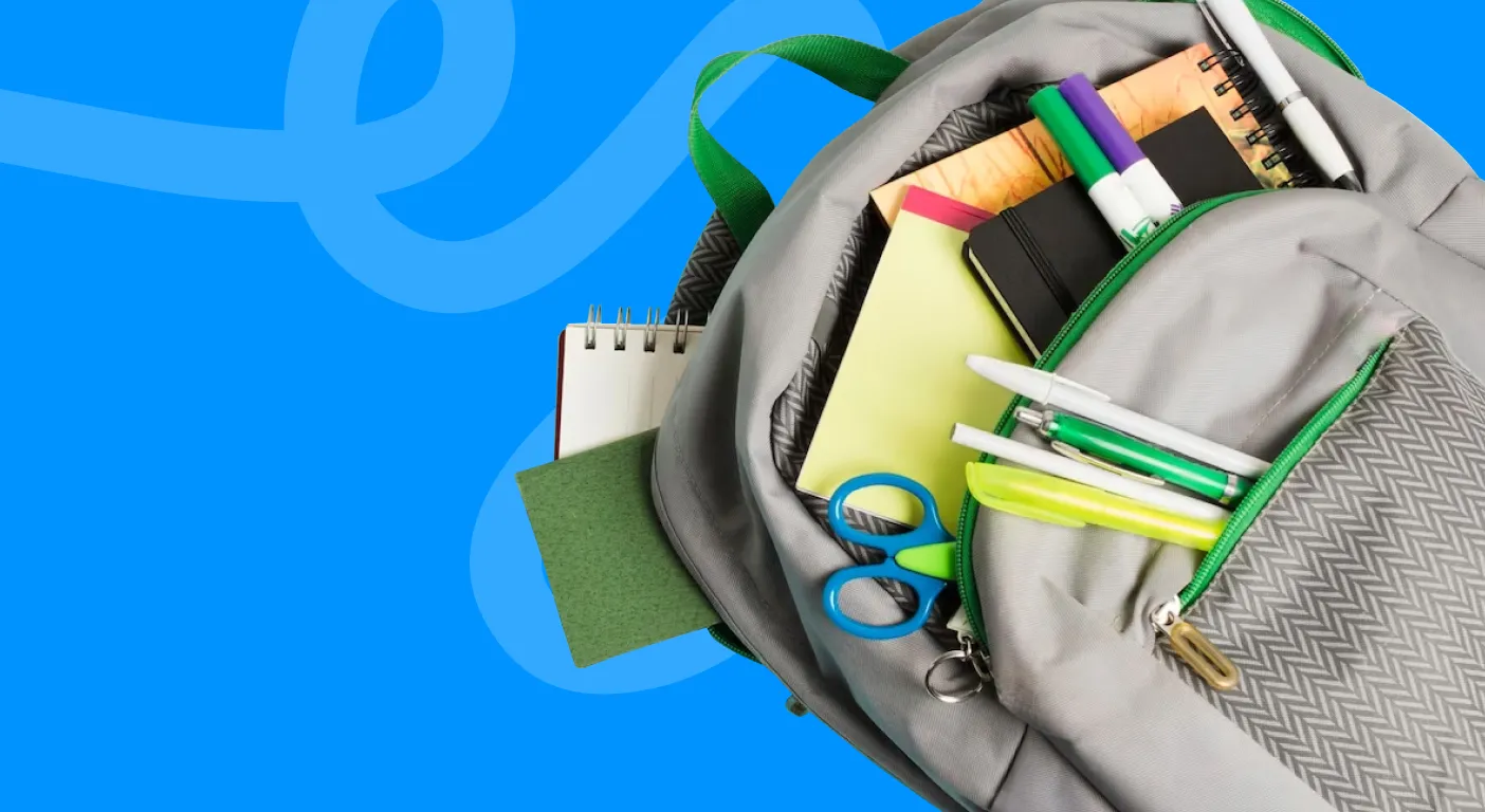 Open backpack packed with notebooks, pens, scissors and school supplies.