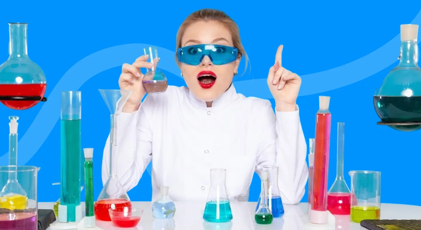 Scientist in a lab coat and safety goggles holding a flask among colourful beakers.