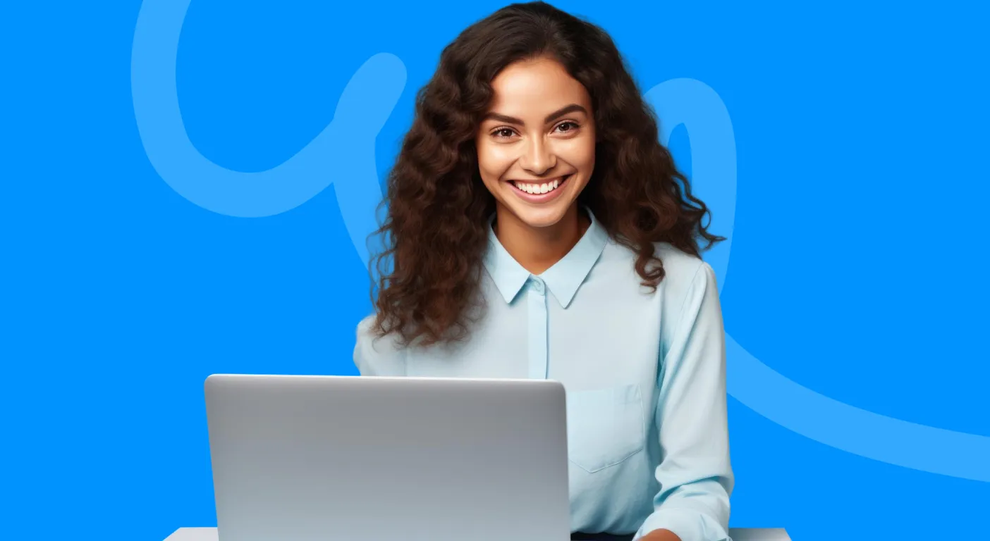 Smiling woman in a pale blue shirt sitting behind an open laptop.