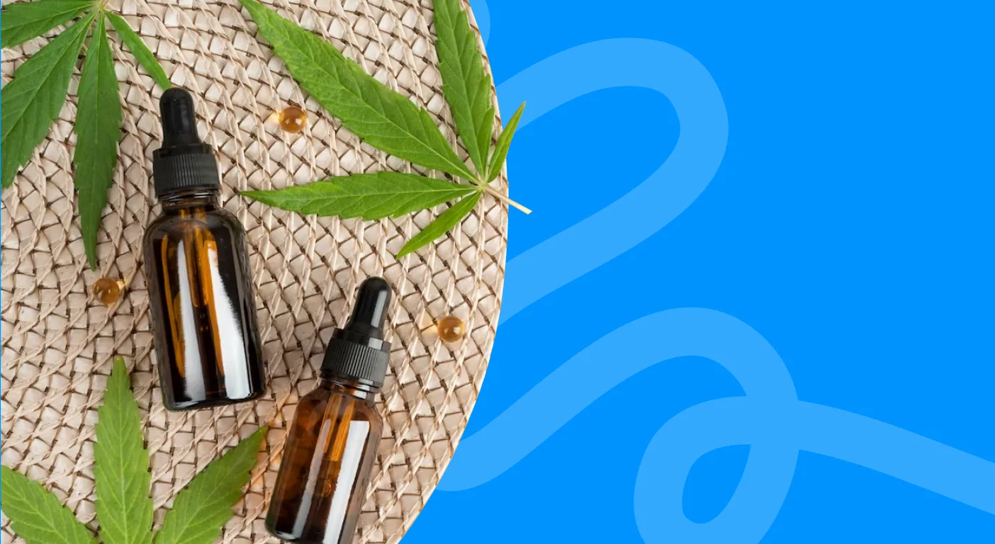 Two amber CBD tincture bottles on a woven mat with hemp leaves.