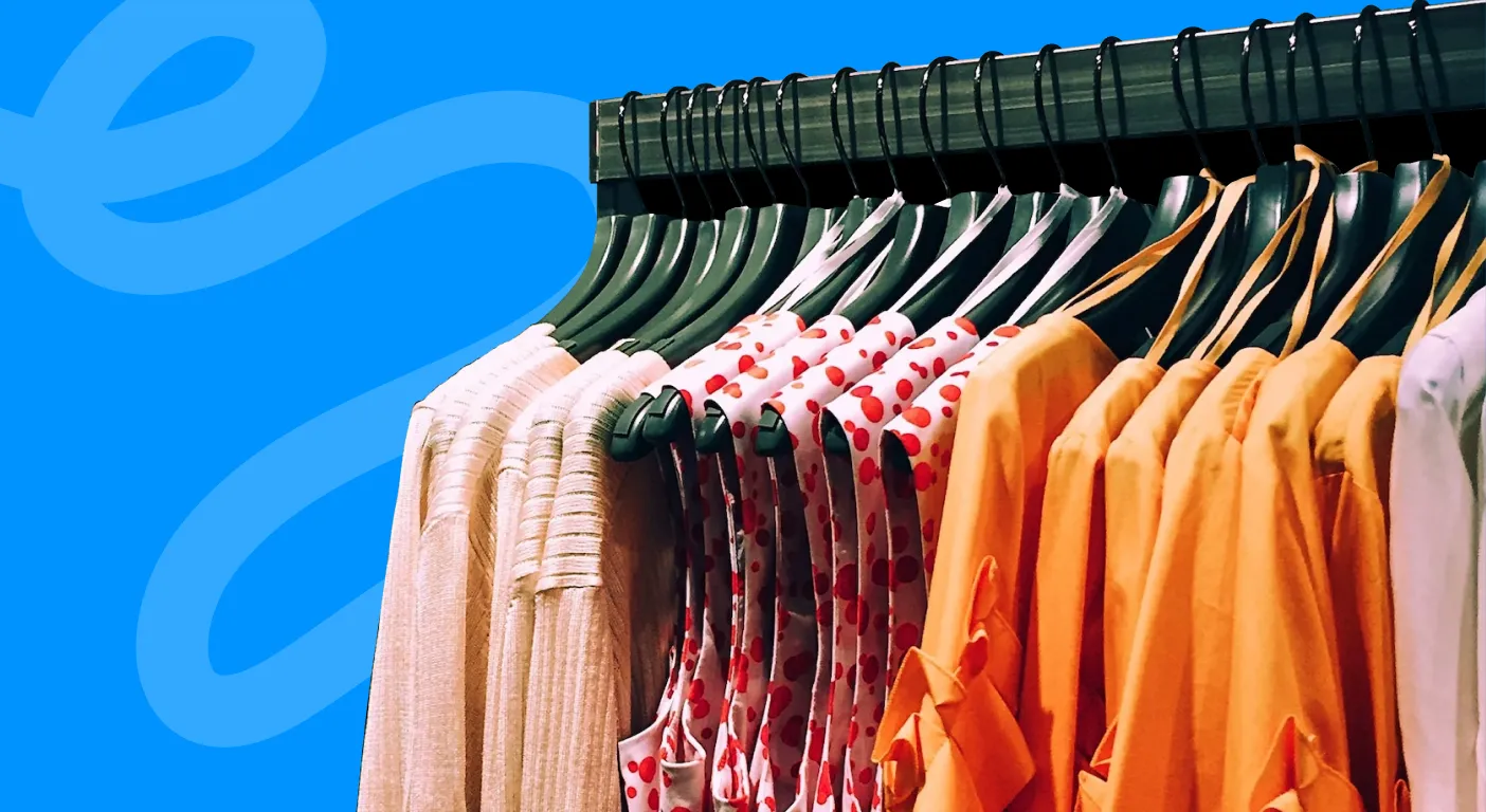 Rail of pink, floral and orange clothing on matching hangers.