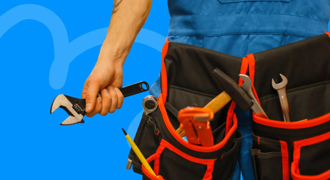 Tradesperson in a tool belt holding an adjustable wrench.