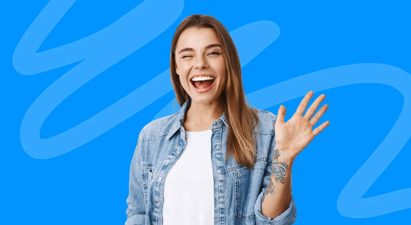 Smiling woman in a denim shirt waving goodbye.
