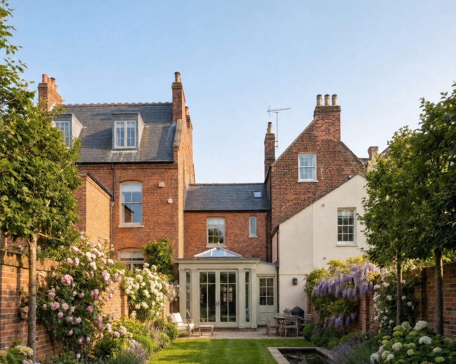 Enhanced photograph of the rear of a Grade II listed Regency terrace: a classical timber orangery opening onto a walled garden of roses, wisteria and lavender in golden light.