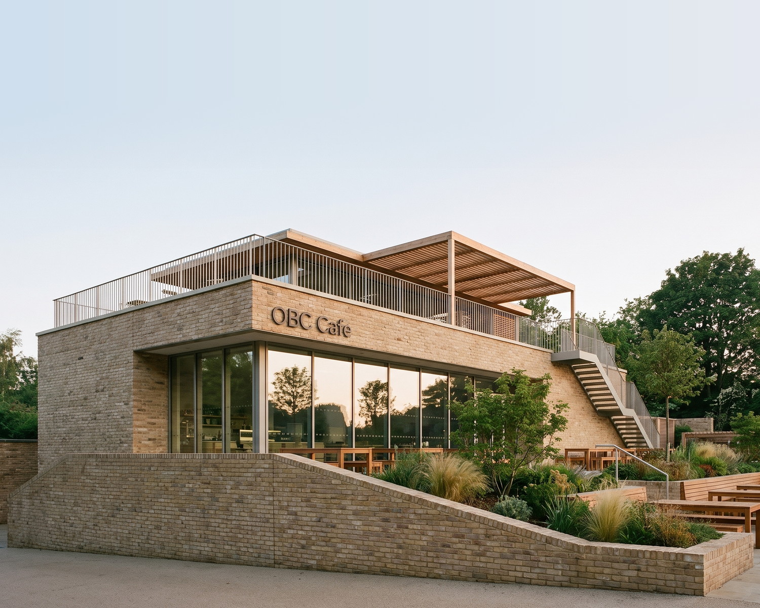 Visualisation of the consented café at the Carlton Road campus in Nottingham: a two-storey building with a fully glazed ground floor under a deep overhang, and a covered roof terrace above, seen at dusk.