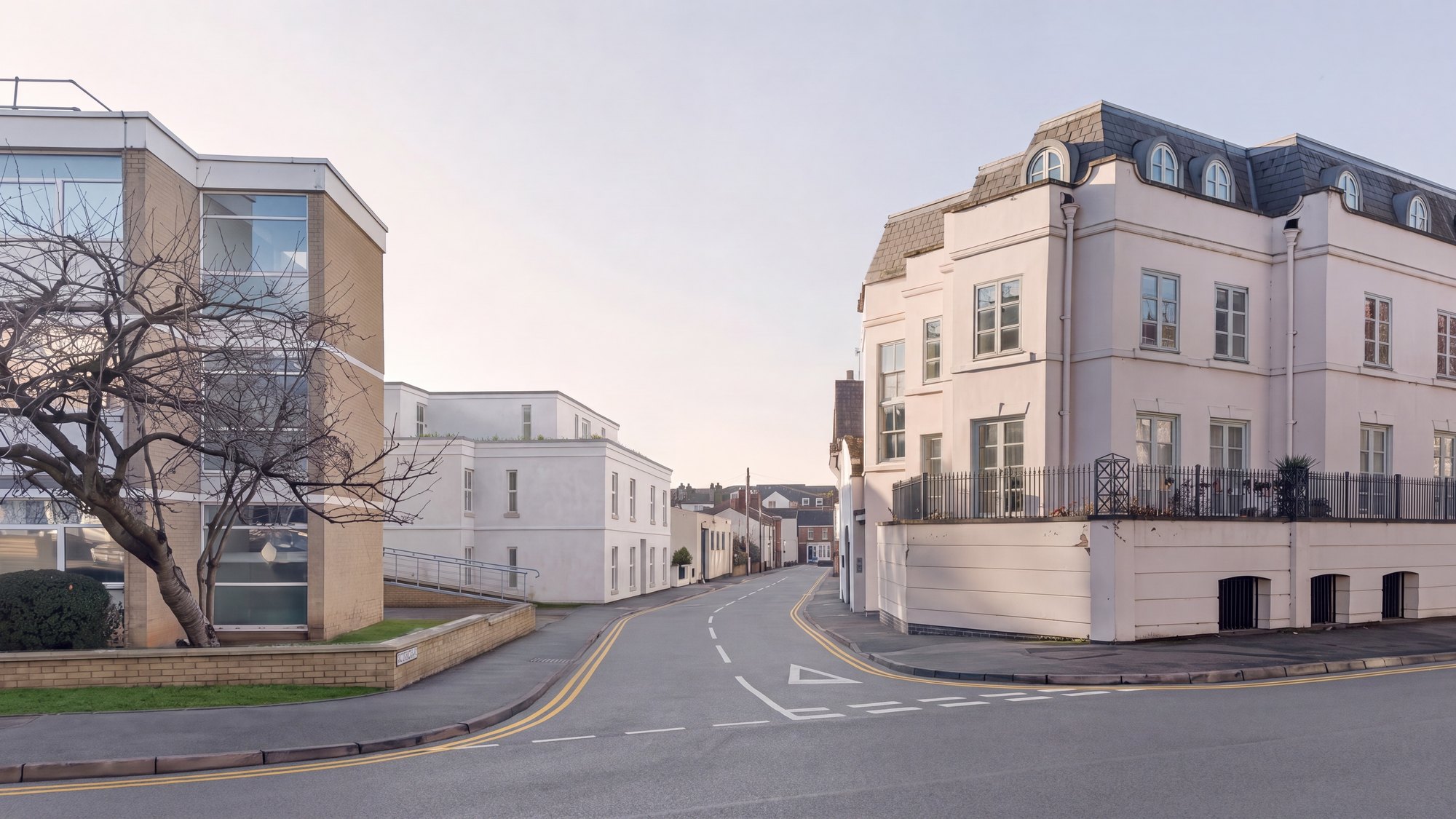 Visualisation of the completed scheme at 16 Cross Street, Royal Leamington Spa, seen down Cross Street toward the Willes Road junction: the new three-storey white rendered apartment building with its set-back top floor and rooftop planting sits quietly between a brick and glass office and a pale rendered building with a slate mansard roof