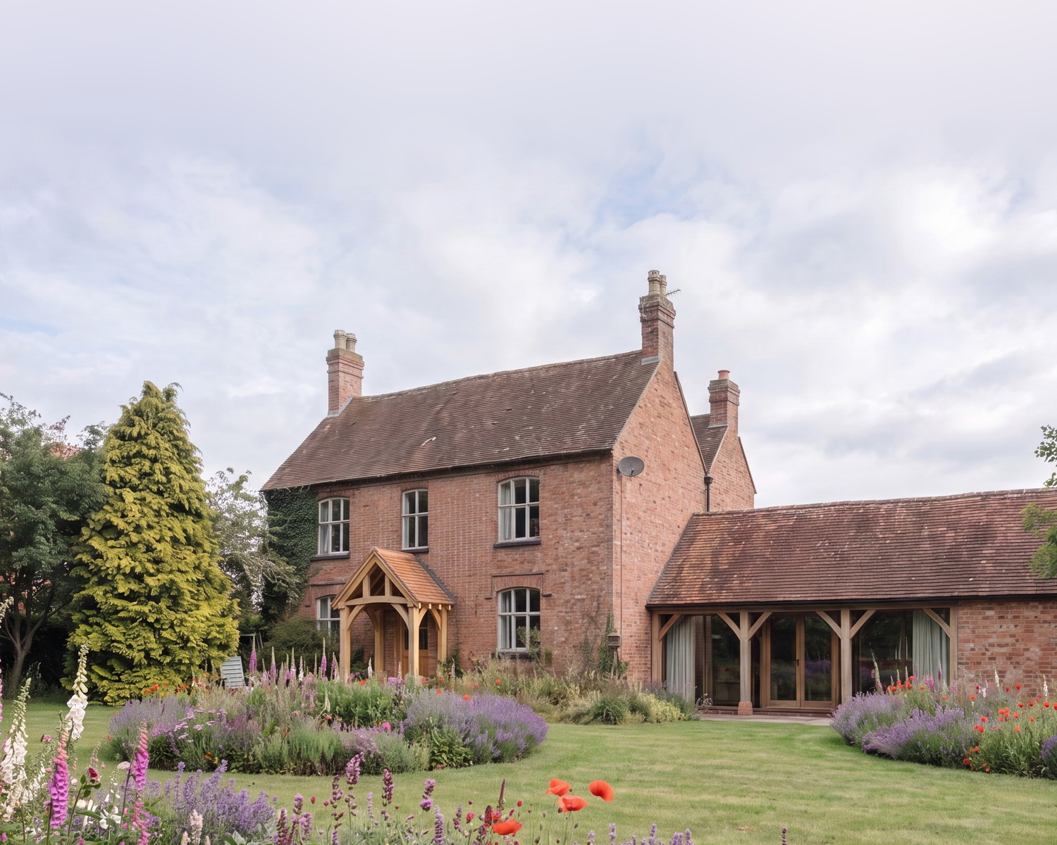 Visualisation of Cannings Farm, Norton Lindsey, by Rickett Architects: a two-storey red brick farmhouse with a green oak entrance porch, joined to a lower former agricultural building with an open oak loggia, seen across the garden.