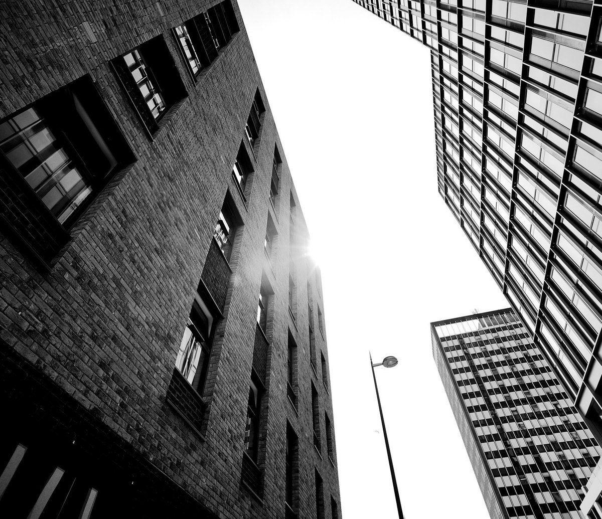Photograph looking up between the completed brick building at Tennant Street, Birmingham and a neighbouring glazed tower, with a street light between them and the city sky above