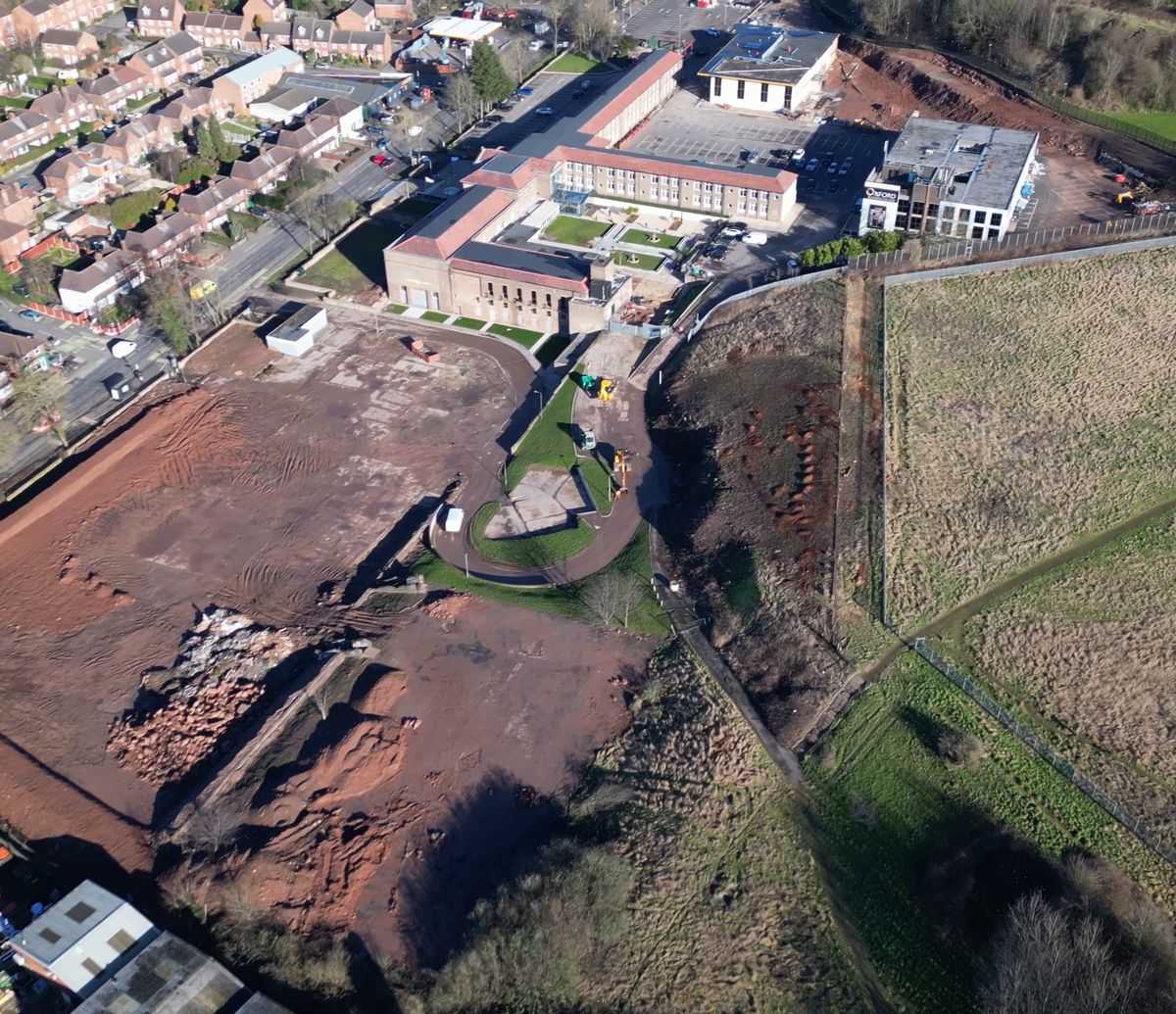 Aerial photograph of the Oxford Business College campus on Carlton Road, Nottingham, from the January 2025 drone survey, looking back across the whole site: the main college building at the centre, cleared brown earth around it, and the open southern land in the foreground showing the full extent of the six hectare campus
