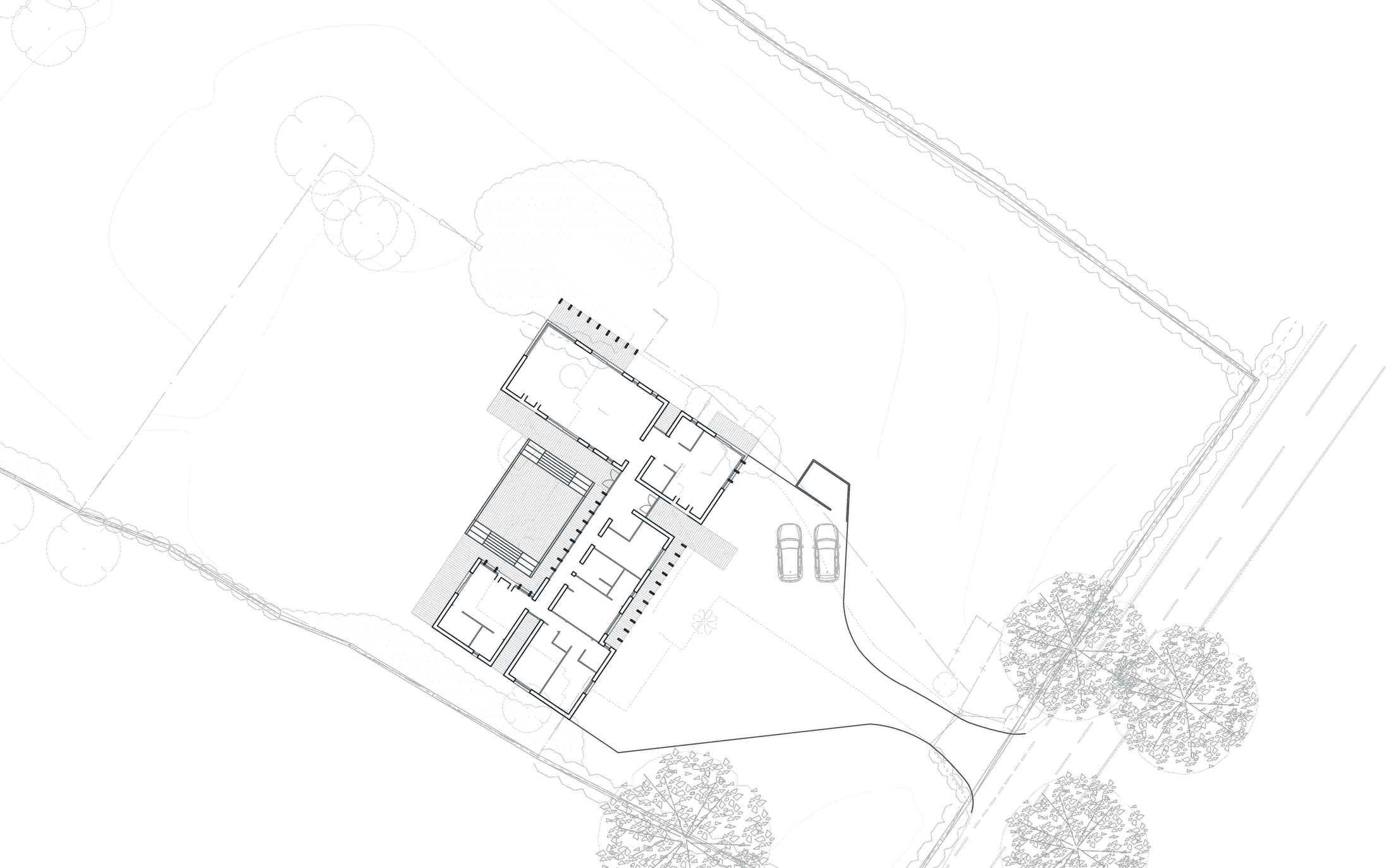 Consented site plan at Hatton: the U shaped house drawn in the centre of a large plot, a drive curving to a parking area with two cars, mature trees drawn as fine canopies along the road frontage at the right, hedgerow boundaries, and surveyed contours across the paddock