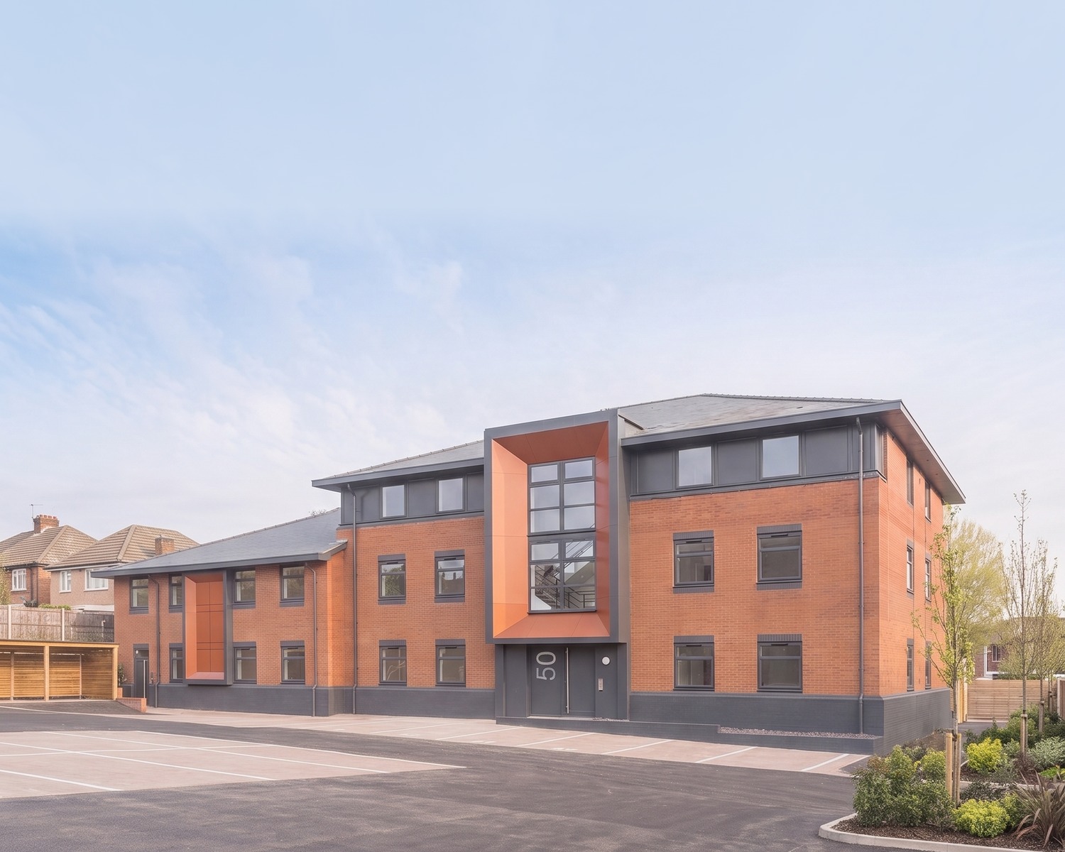 A Rickett Architects visualisation of the completed Sheldon Court, Birmingham: two former office blocks converted to sixty-four apartments, in red brick with grey hipped roofs, anthracite window surrounds and a tall projecting orange entrance feature.