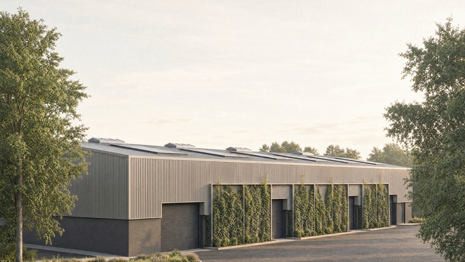 Visualisation of the consented warehouse extension at Aldridge Road, Perry Barr: a long flat-roofed building clad in pale vertical profiled sheeting above a dark plinth, with roller-shutter loading doors set between tall bays of planted green wall, rooflights along the roof, and a new service road curving away in the foreground