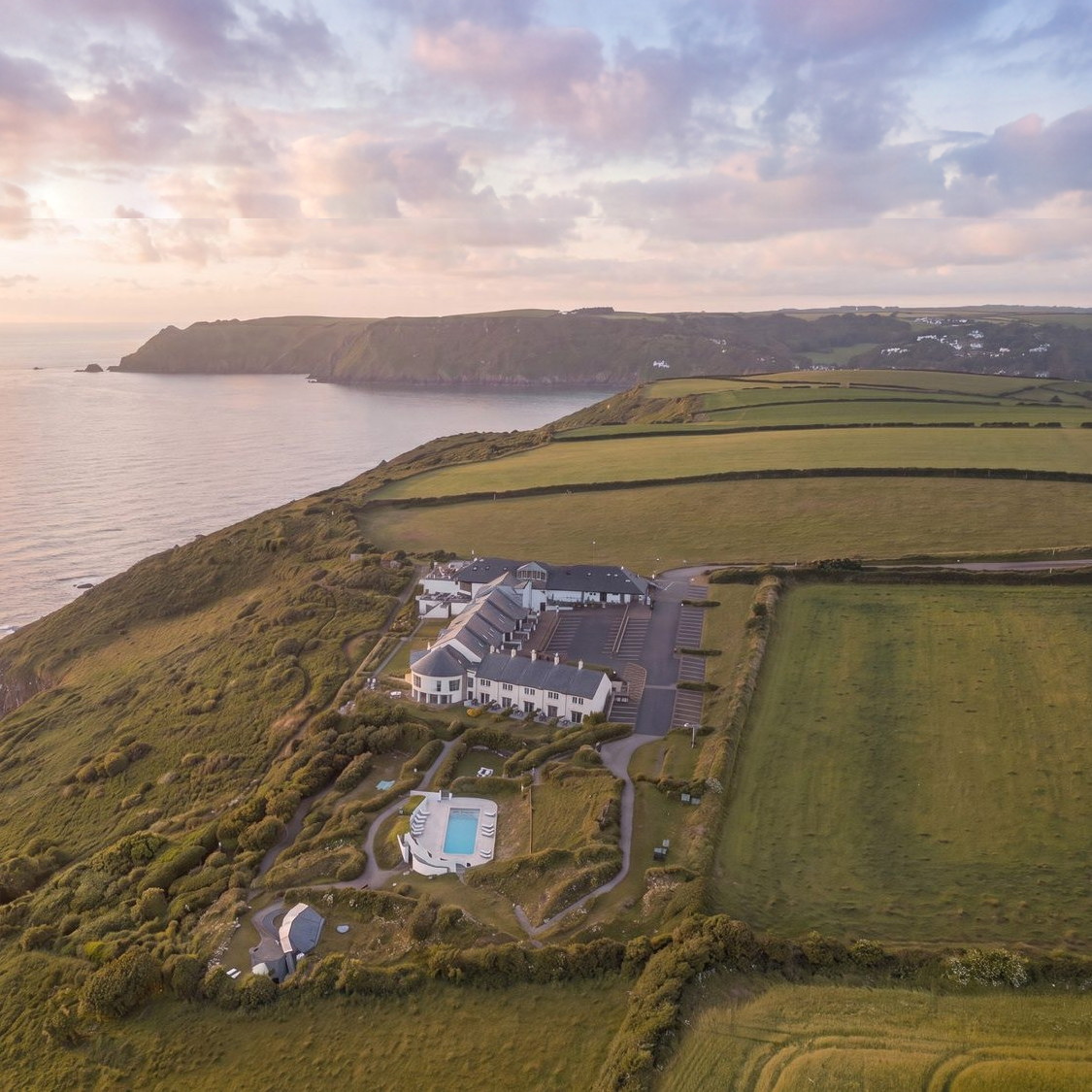 Rickett Architects visualisation of the clifftop resort at Gara Rock, South Devon: a hotel, cottages and apartments above the sea at first light.