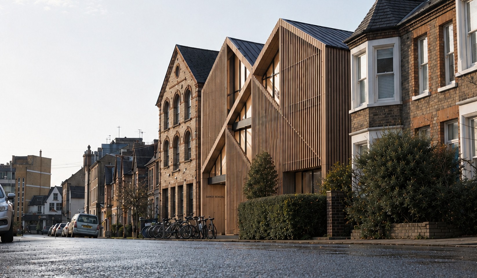 A Rickett Architects visualisation looking along the same street: a timber-screened building with two pitched gables standing between the retained brick dance school building and the bay-fronted houses