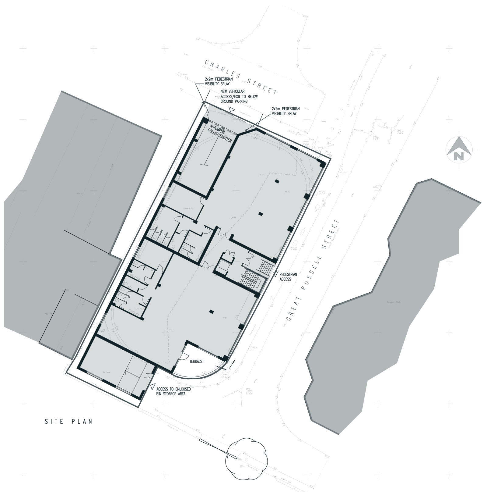 Approved site plan: a long rectangular building filling a corner plot between Charles Street at the top and Great Russell Street on the right, two offices either side of a central entrance and stair, a vehicle entrance with a roller shutter off Charles Street, a curved terrace at the bottom corner, and neighbouring buildings drawn in grey on both sides