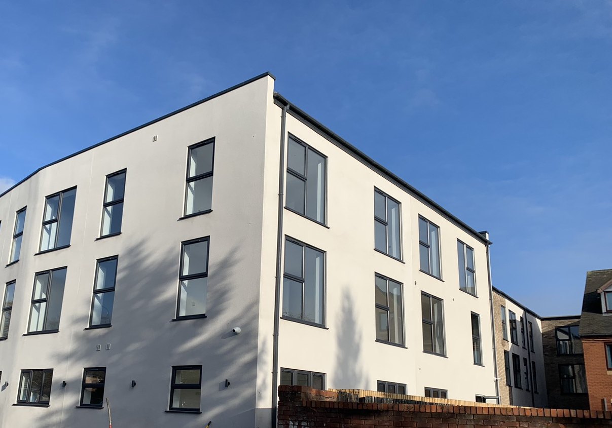 Photograph of the rear in December 2022: a three-storey white rendered block with dark grey windows