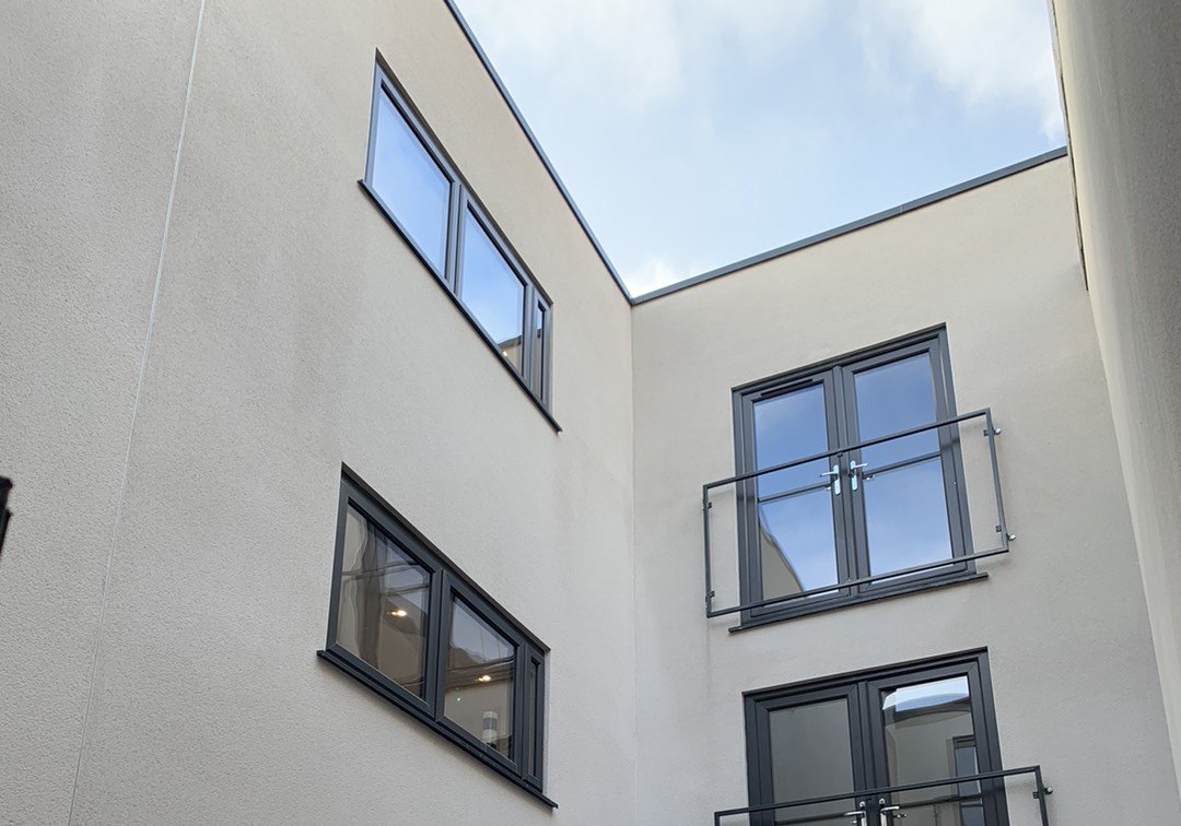 Photograph looking up a light well in December 2022: white render, French doors and Juliet balconies