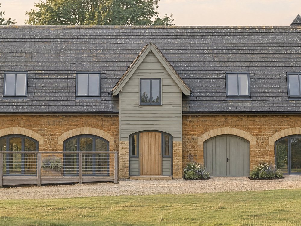 Closer visualisation of the timber-clad entrance gable and its arched door, set between stone walls