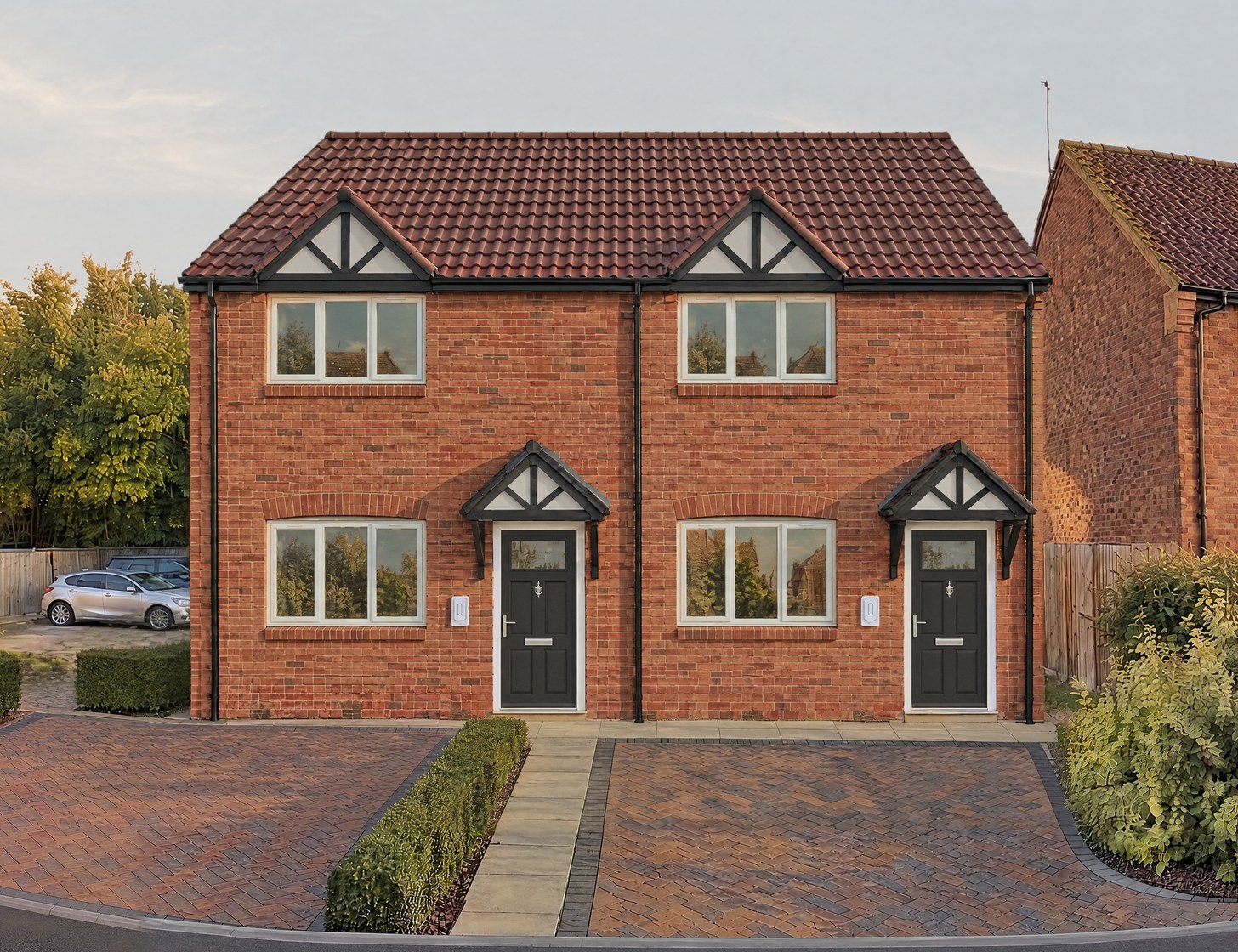 A closer view of the visualisation: dark front doors under gabled canopies and block-paved parking